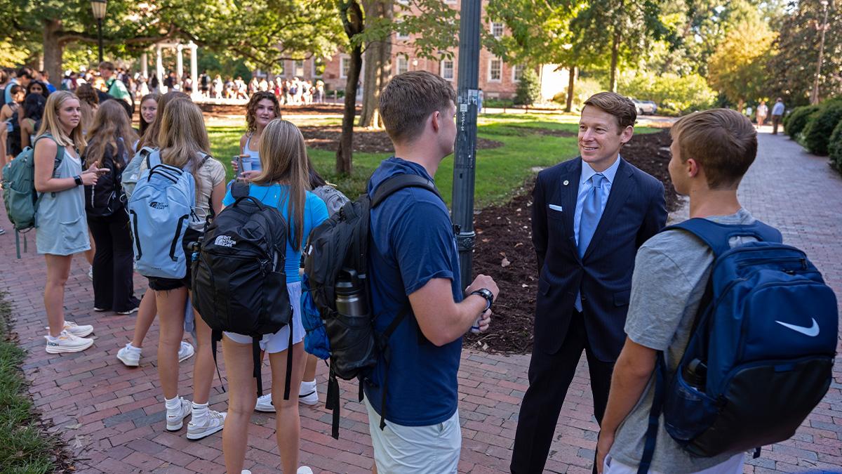 Chancellor Lee H. Roberts speaking to students waiting in line to take a sip from the Old Well.